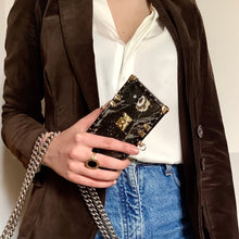 Load image into Gallery viewer, Black marble iPhone case by PURITY with gold accents and a crossbody strap.