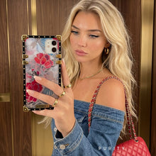 Load image into Gallery viewer, Woman holding a phone with a luxury floral iPhone case in front of a wooden door
