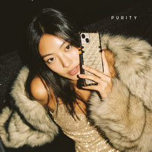 Load image into Gallery viewer, Woman holding a luxury golden iPhone case with woven design by PURITY.
